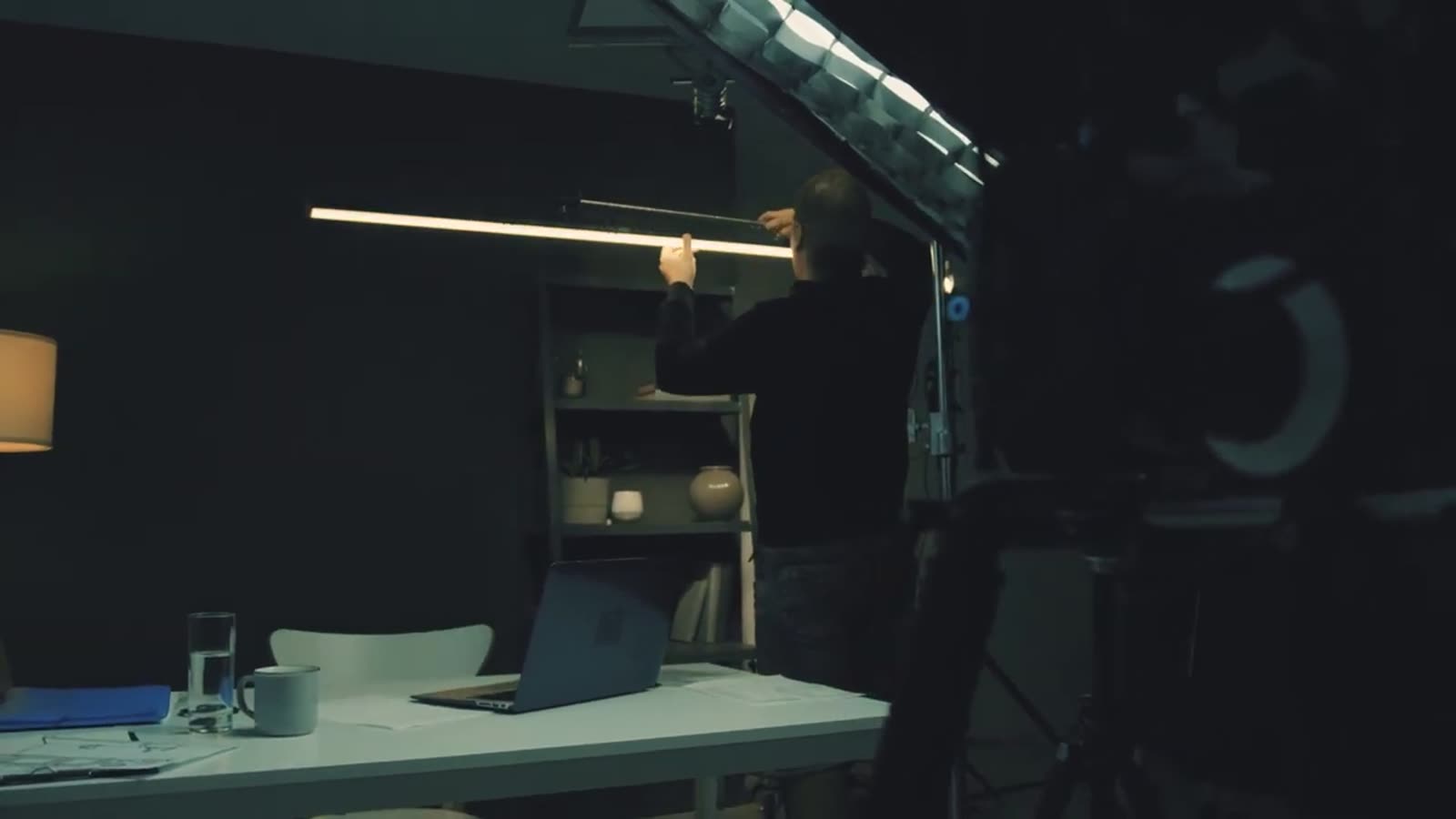 Camera operator behind a cinema rig on a darkened set.